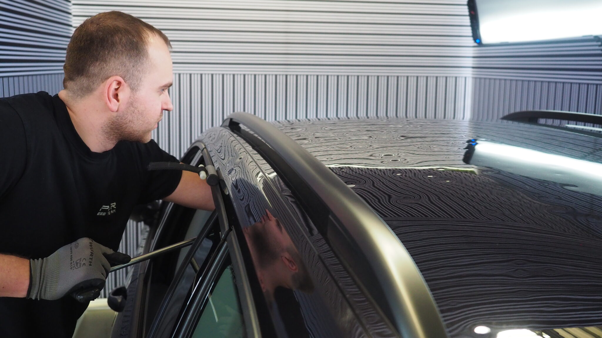 Paintless dent repair technician working on vehicle panel